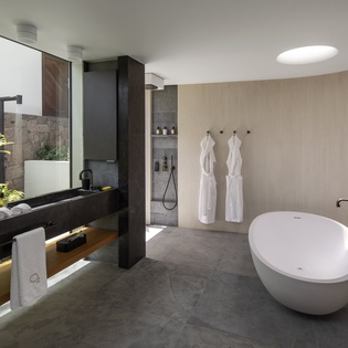 Unwind in your luxurious spa-like bathroom with a soaking tub, rain shower, and tropical garden views through floor-to-ceiling windows.