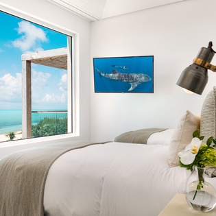 Wake up to stunning turquoise waters from your oceanfront bedroom, where plush bedding and coastal artwork create your perfect seaside retreat.