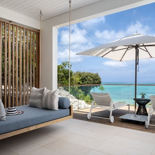 Unwind in your private oceanfront haven where the indoor-outdoor boundary disappears, revealing endless turquoise waters from your stylish seating area.