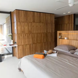 Step into your stylish retreat with warm wood paneling, a ceiling fan for comfort, and a peaceful view of your private outdoor space—your restful escape awaits.