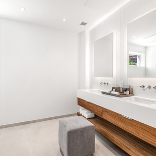 Immerse yourself in this sleek, spa-like bathroom where warm wood meets pristine white stone for your daily retreat.