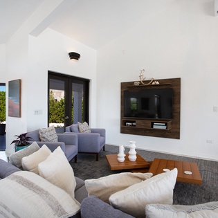 Sink into plush seating in your bright, open living room, where vaulted ceilings and tropical views create the perfect space to unwind after a day exploring.