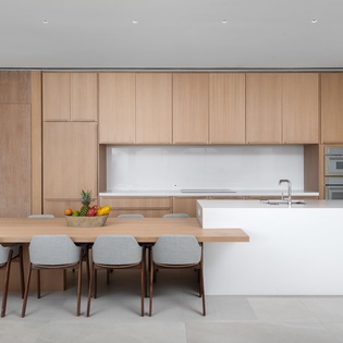 Cook and dine in your sleek modern kitchen featuring warm wood cabinetry, pristine white countertops, and spacious island seating.