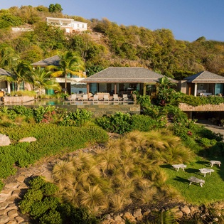 Hillside villa estate with tropical gardens and multiple pavilions set against lush natural landscape.