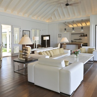 Unwind in this elegant open-plan living space with vaulted ceilings, plush white sofas, and warm wood floors that invite you to relax.