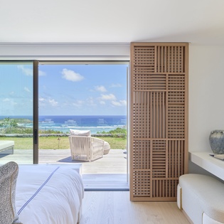 Wake up to endless ocean views from your serene bedroom, where floor-to-ceiling windows frame the sparkling sea perfectly.