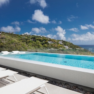 Stunning infinity pool with crystal-clear waters and breathtaking sea views across lush tropical hillsides.