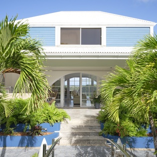 Stunning tropical property with elegant white facade and lush palm gardens creating a perfect island retreat.