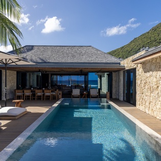 Luxury villa showcases stone architecture, private pool, and mountain backdrop in a tropical paradise setting.