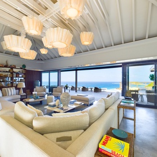 Your spacious living room opens to stunning sea views through floor-to-ceiling windows, where plush sofas invite relaxation under elegant pendant lighting.