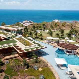 Stunning oceanfront estate features modern architecture with rooftop gardens, expansive pool, and direct beach access.