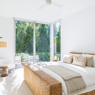 Wake up to sunlight streaming through floor-to-ceiling windows in your serene bedroom, where natural textures and peaceful garden views create your perfect retreat.