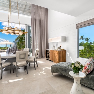 Unwind in your elegant open-plan living space where tropical views through floor-to-ceiling windows create the perfect backdrop for memorable meals.