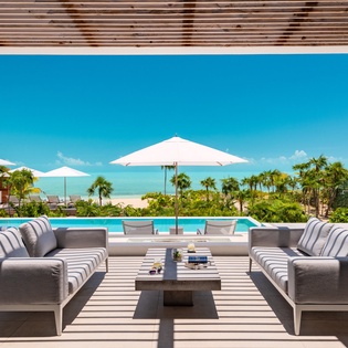 Sink into plush seating on your private terrace while the infinity pool frames turquoise waters and swaying palms ahead.