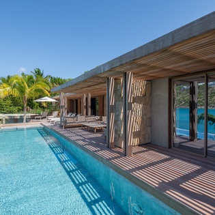 Sleek modern villa showcasing contemporary architecture with infinity pool and tropical surroundings in an exclusive hillside setting.