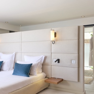 Sink into plush comfort with crisp linens and elegant accent pillows in this serene bedroom retreat, featuring modern lighting and a private connection to your outdoor space.