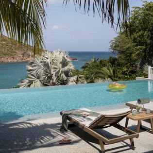 Unwind by your private infinity pool where crystal-clear waters blend seamlessly with stunning ocean views through swaying palms.