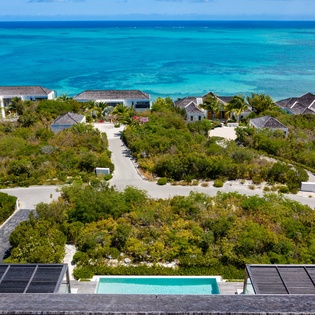 Aerial view of a luxury beachfront resort community with pristine turquoise waters and tropical landscaping.