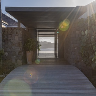 Modern stone walkway leads to stunning ocean views through the property's elegant entrance corridor.
