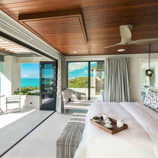 Wake up to stunning turquoise waters framed by floor-to-ceiling glass doors that open to your private balcony. The warm wood ceiling and coastal-chic décor create a serene, luxurious retreat.