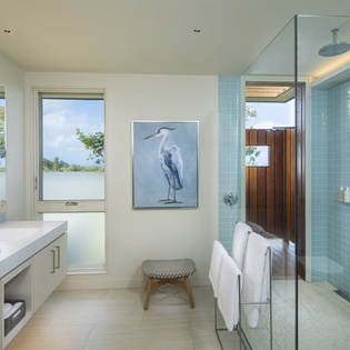 Your spa-like bathroom awaits with a rainfall shower, elegant blue tiles, and peaceful water views that transform your daily routine into pure relaxation.