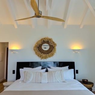 Picture yourself waking up in this serene bedroom with vaulted ceilings and soft morning light. The plush bedding invites total relaxation while coastal-inspired décor creates your peaceful island escape.