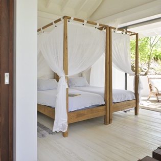 Drift off to sleep in your romantic four-poster bed with flowing white curtains, where tropical breezes and natural light create the perfect sanctuary.