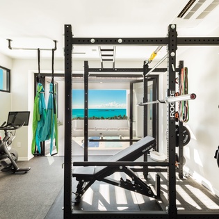 Your private fitness center overlooks turquoise waters, blending serious workouts with a stunning tropical setting—barbells, cardio, and pure ocean inspiration.
