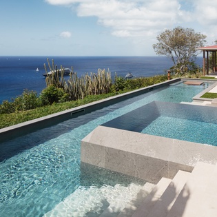 Stunning infinity pool overlooking the azure Caribbean sea, with luxury villa and tropical gardens creating the perfect island escape.