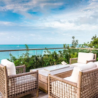 Sink into plush wicker seating while crystal-clear turquoise waters stretch endlessly before you on this stunning oceanfront terrace.