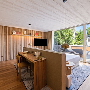 Unwind in your stylish living space with warm wood tones, floor-to-ceiling windows, and seamless outdoor views.