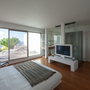 Wake up in your modern bedroom with floor-to-ceiling windows opening to a private terrace and stunning sea views.