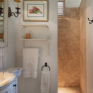 Step into your elegant bathroom, where warm travertine and charming décor create a serene retreat for your morning rituals.