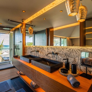 Refresh in your luxurious double-sink bathroom, where natural light and tropical breezes blend with warm wood tones and elegant fixtures. The genuine ocean view through your windows sets the perfect backdrop.