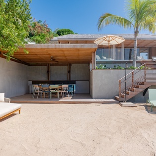 Modern beachfront villa featuring contemporary architecture surrounded by tropical palms and lush landscaping.
