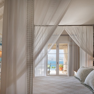 Drift off in a dreamy canopy bed as soft curtains frame your private ocean view and terrace beyond.