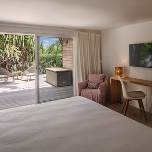 Step into your serene bedroom retreat where sunlight filters through sliding doors, revealing your private terrace with lush garden views. A cozy armchair beckons, and modern touches keep you comfortable.