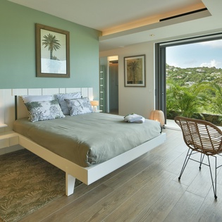 Wake up to stunning tropical views from your serene bedroom, where modern comfort meets natural beauty through floor-to-ceiling windows.