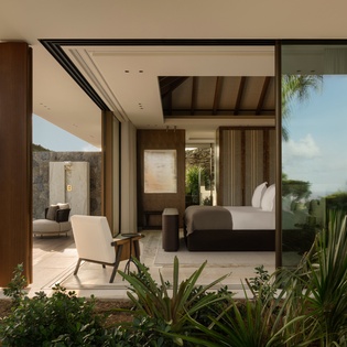 Your sophisticated bedroom flows seamlessly onto a private terrace, where tropical gardens frame stunning mountain views beyond.