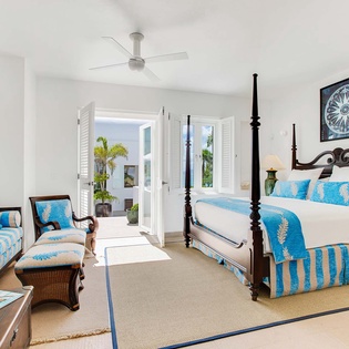 Wake up refreshed in your elegant four-poster bed, then step through bright shuttered doors to your private outdoor retreat—your perfect coastal escape awaits.