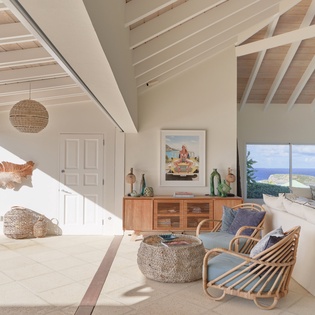 Settle into this sun-drenched living space with coastal-inspired design. Natural textures and ocean blues invite you to unwind as sunlight filters through soaring ceilings and expansive windows.