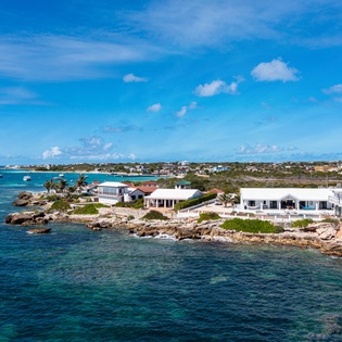 Stunning coastal property perched on rocky shoreline with turquoise Caribbean waters and white sandy beaches. Modern waterfront homes offer direct ocean access in this peaceful island setting.