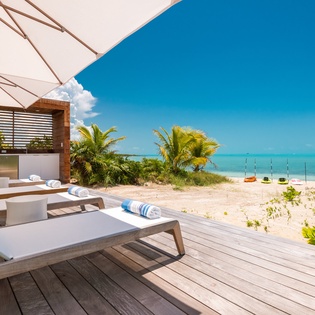Unwind on your private deck overlooking pristine turquoise waters, where soft loungers await beneath tropical shade and the beach is just steps away.