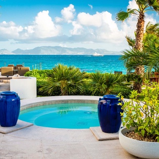 Private pool framed by lush tropical gardens, with turquoise Caribbean waters and mountain vistas beyond. A serene outdoor oasis on this stunning island retreat.