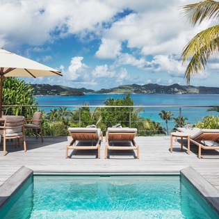 Soak up stunning turquoise views from your private poolside paradise, complete with loungers, dining, and swaying palms—perfect for relaxing in style.