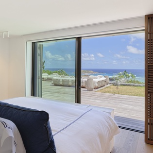 Wake up to breathtaking ocean vistas through floor-to-ceiling windows, where your comfortable bed frames stunning blue waters.