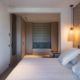 Your modern bedroom features crisp white linens, warm wood accents, and a cozy reading nook perfect for unwinding after exploring.