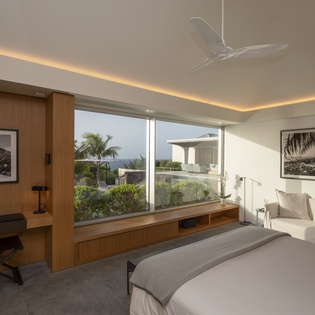 Wake up to tropical views through floor-to-ceiling windows in your serene bedroom retreat with modern amenities and cozy reading nook.