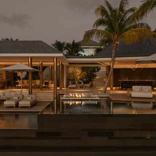 Luxurious modern villa showcases stunning tropical architecture with infinity pool, palm trees, and warm evening lighting creating an elegant resort atmosphere.