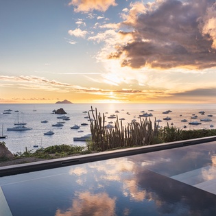 Stunning infinity pool overlooks the sea as golden sunset light dances across the water, creating perfect reflections for an unforgettable evening.
